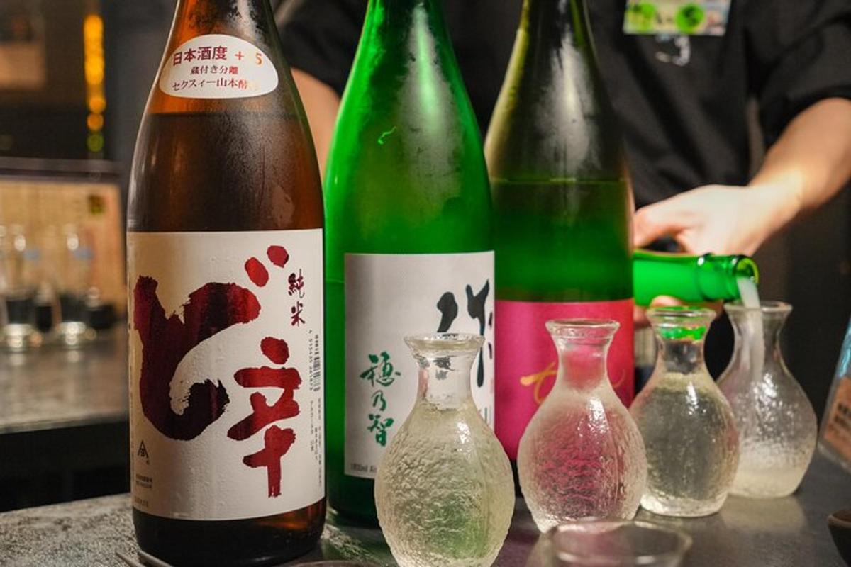 tiga botol wain duduk di atas meja dengan pasu