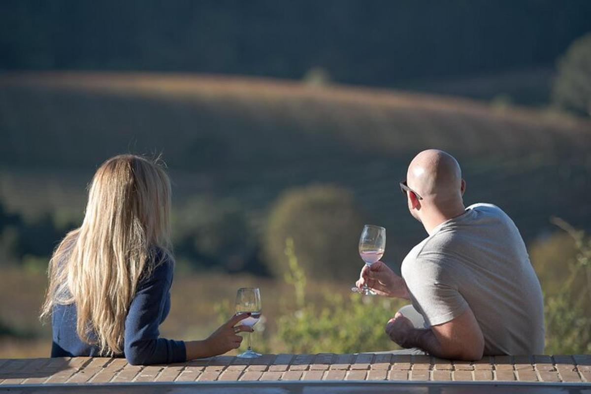 un uomo e una donna seduti su un tavolo con bicchieri di vino