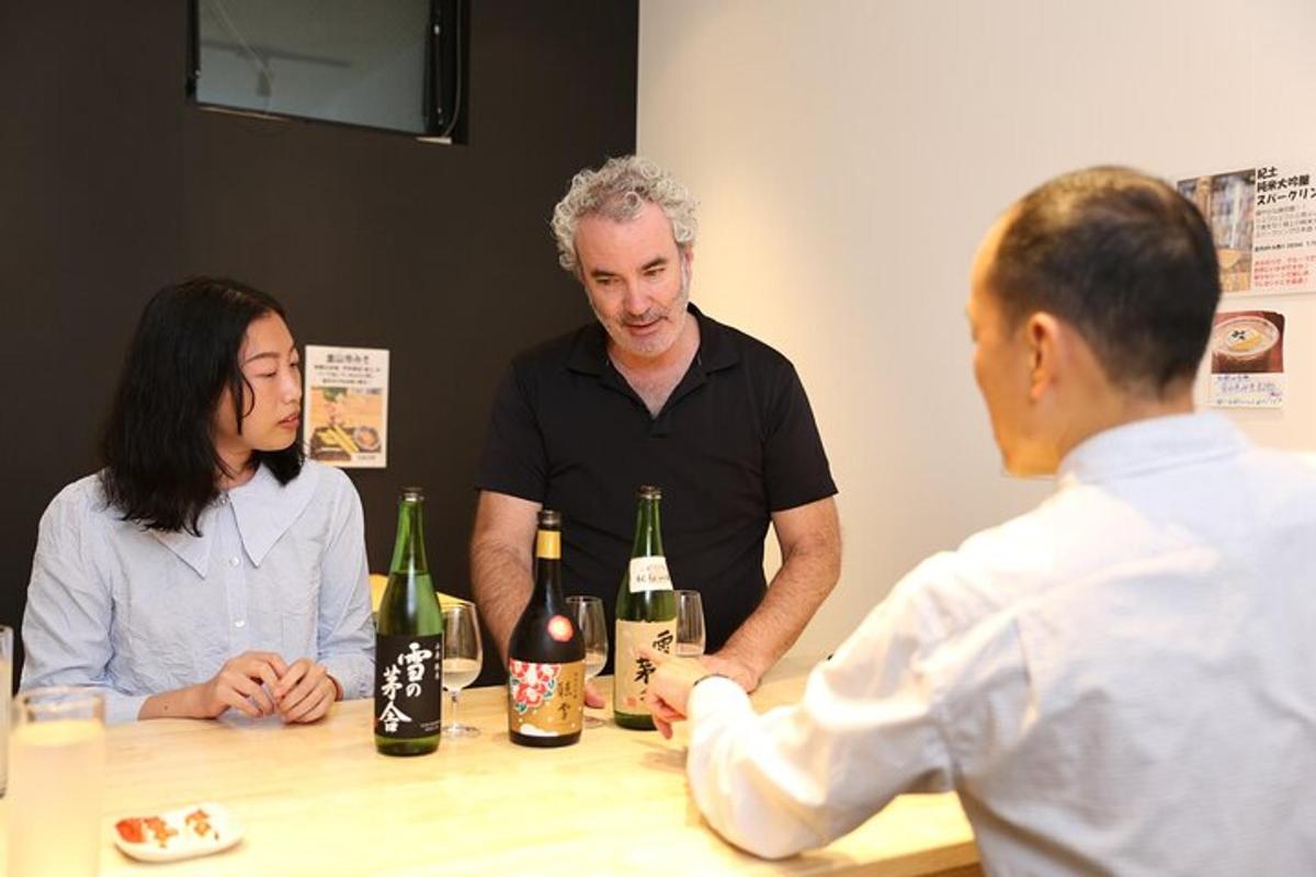 three people sitting around a table with bottles of wine