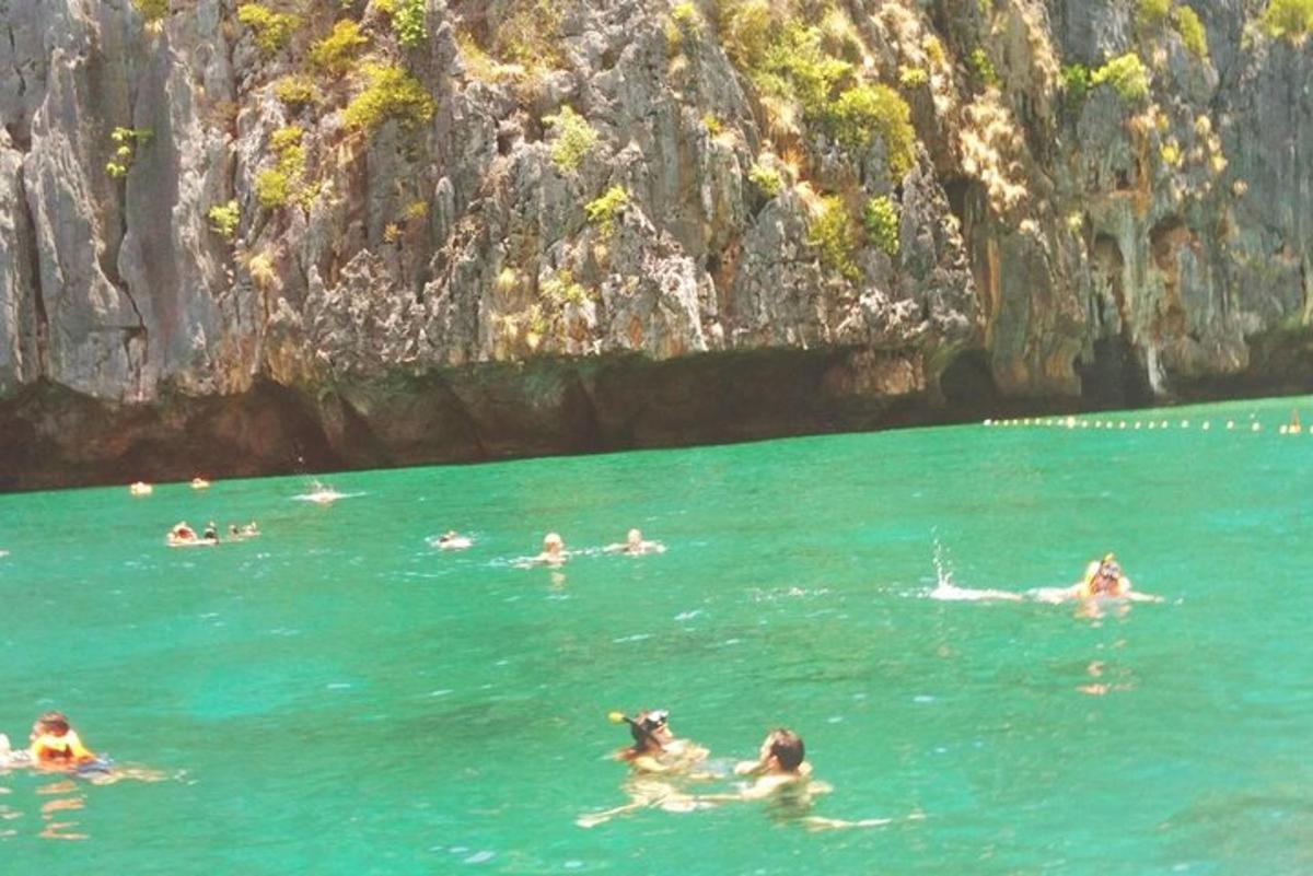 Μια ομάδα ανθρώπων που κολυμπούν στο νερό κοντά σε ένα βουνό