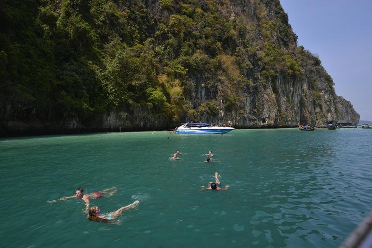 eine Gruppe von Menschen, die im Wasser in der Nähe eines Berges schwimmen