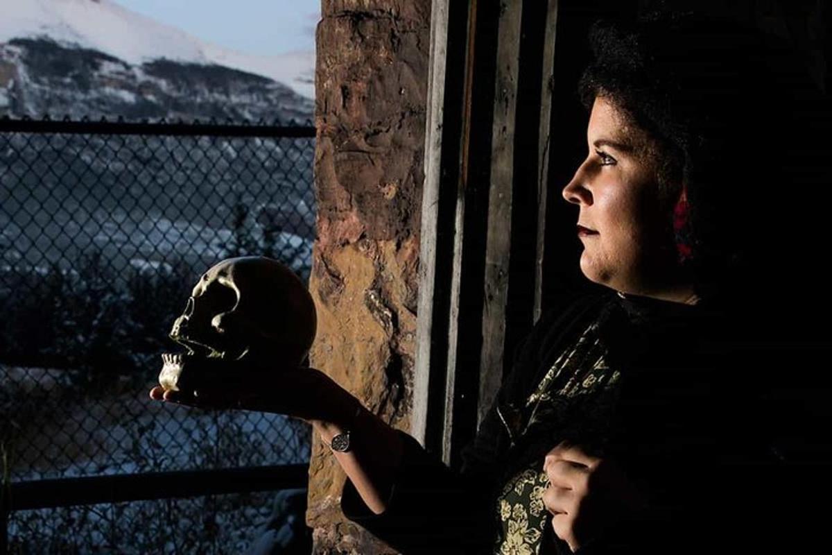 a woman looking out of a window with a skull