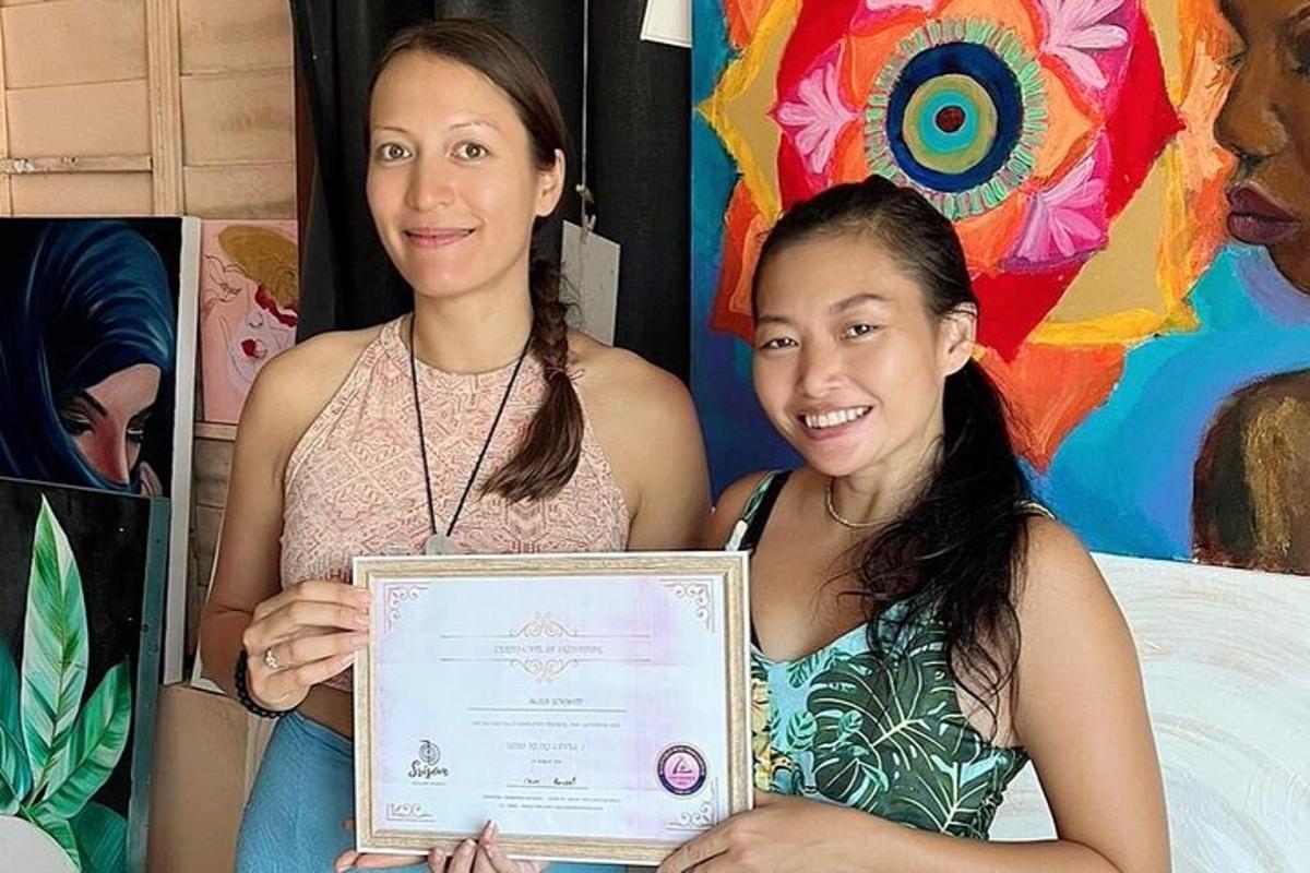 Dve ženy držia certifikát pred obrazom
