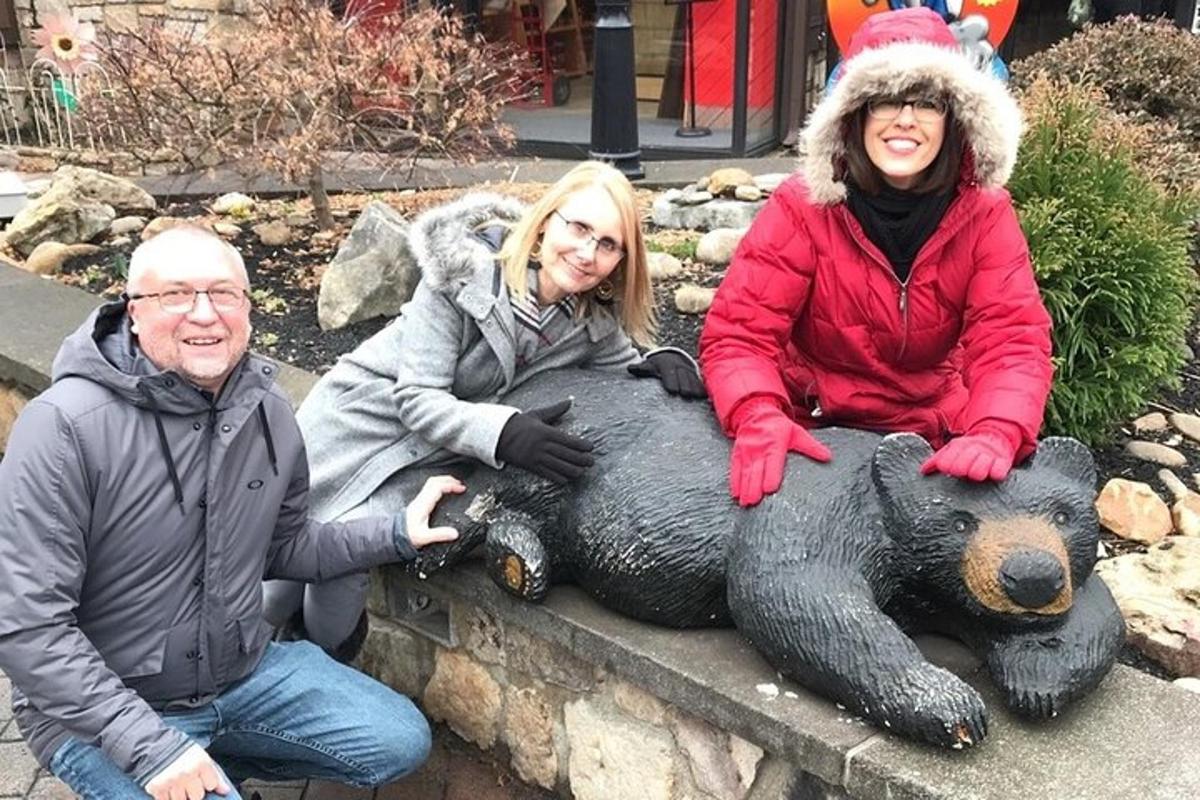 tres persones assegudes en una estàtua d'un ós de peluix