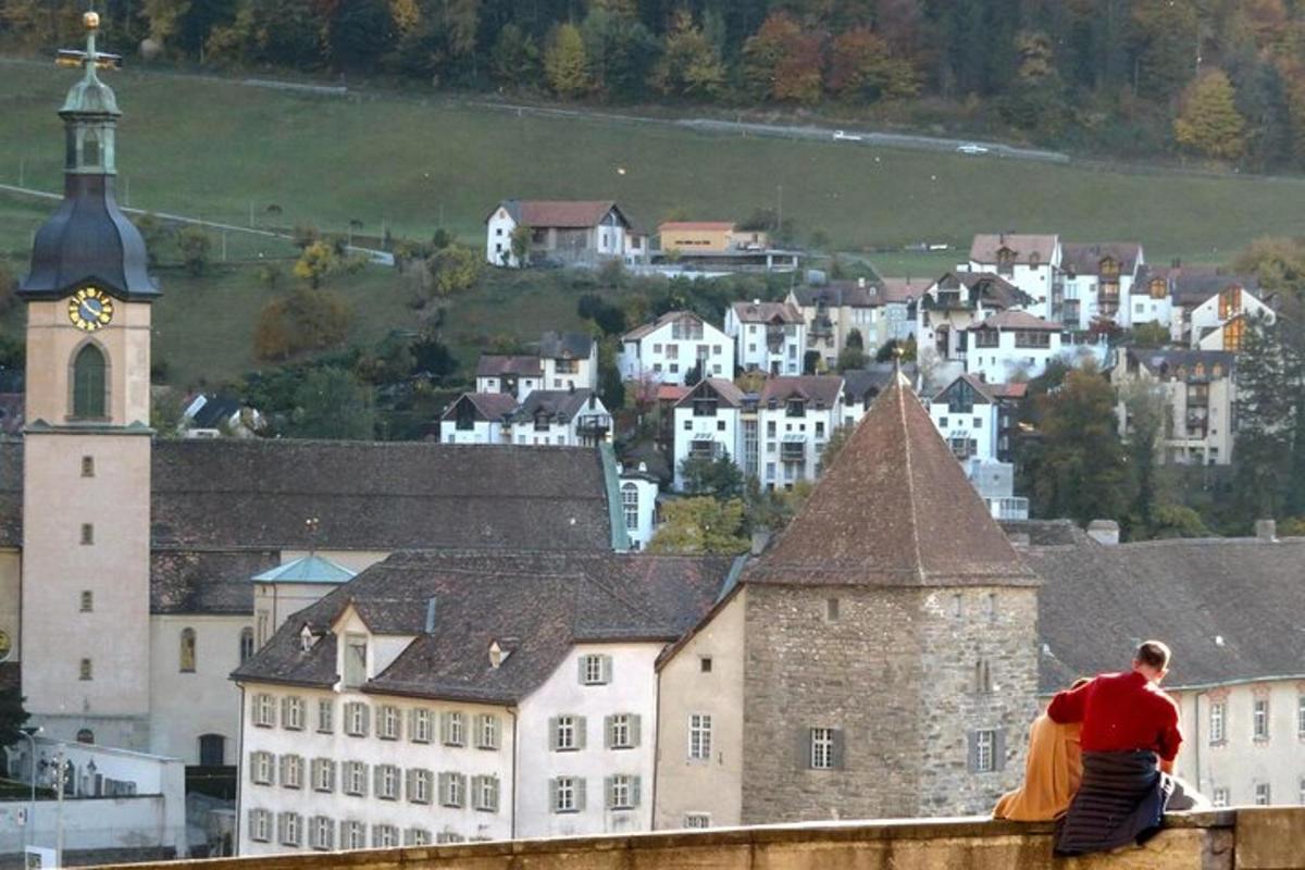 muž sedící na střeše budovy s hodinovou věží