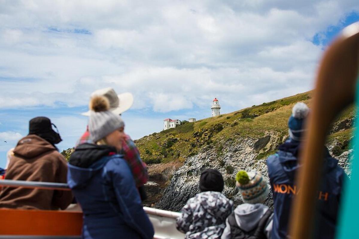 a group of people on a boat looking at a lighthouse