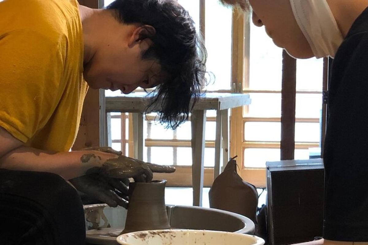 a woman working on a pottery wheel next to another woman