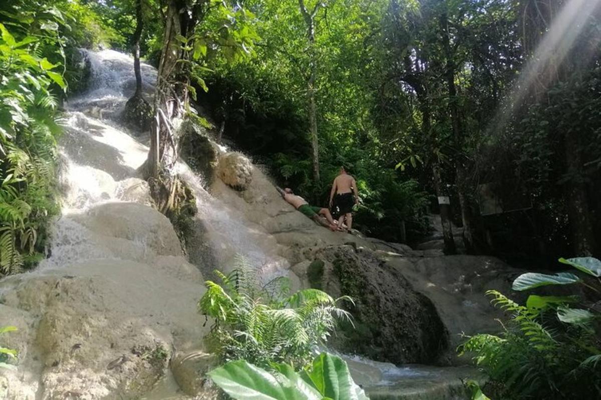 seorang lelaki berdiri di atas batu di sebelah air terjun