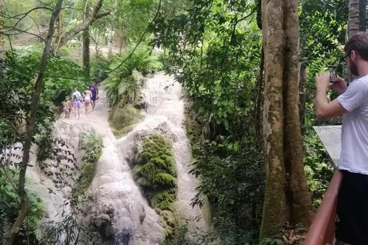 un home fent una foto d'una cascada en un bosc