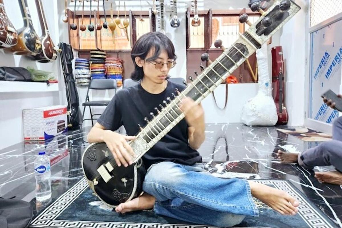 một người đàn ông ngồi trên sàn chơi đàn ghi-ta