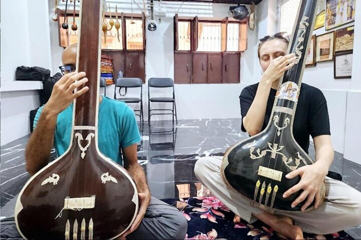 hai người đàn ông ngồi trên sàn với hai cây đàn guitar