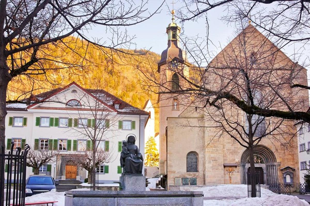 kostel s hodinovou věží a sochou před ní