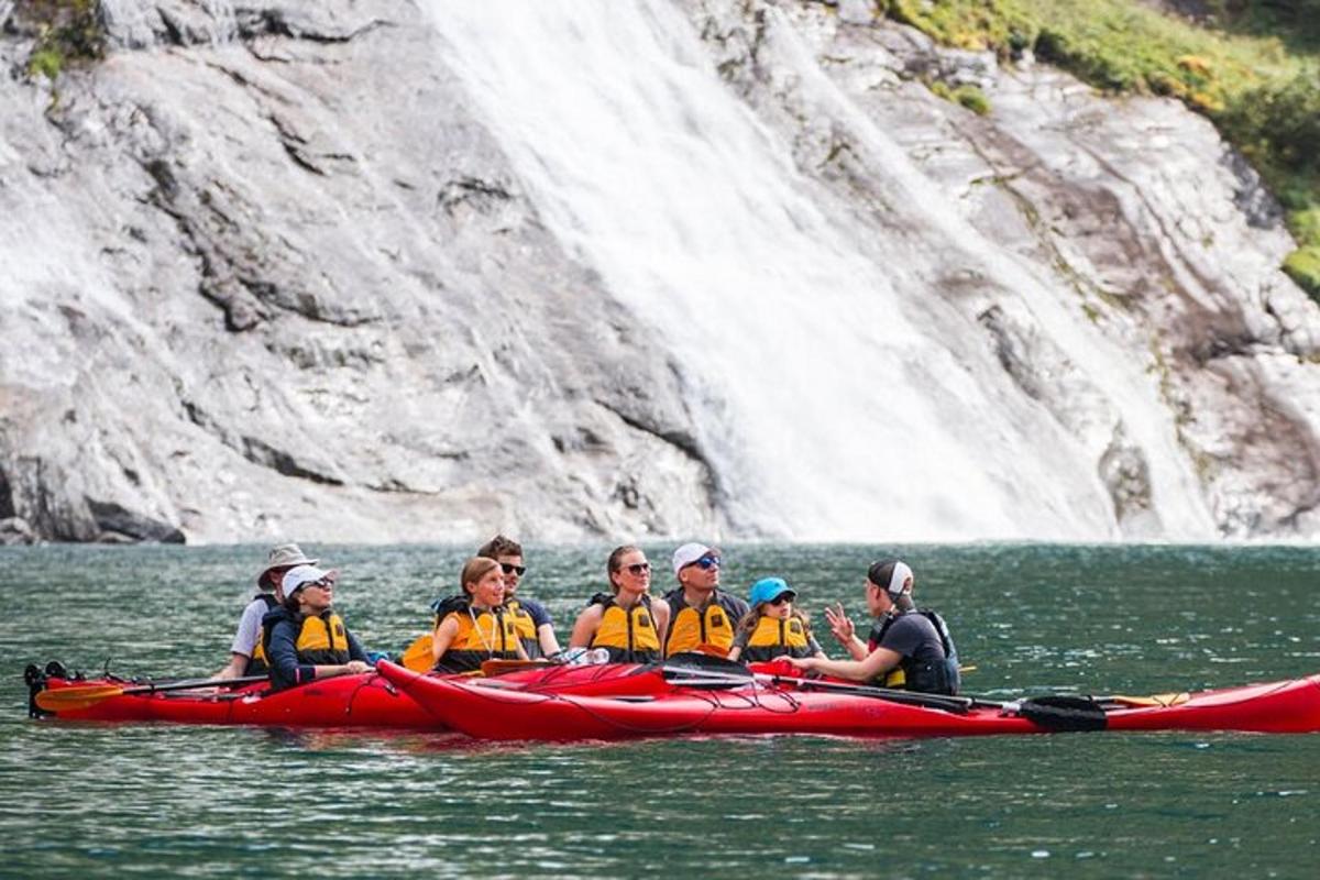 a group of people in a red kayak in front of a waterfall