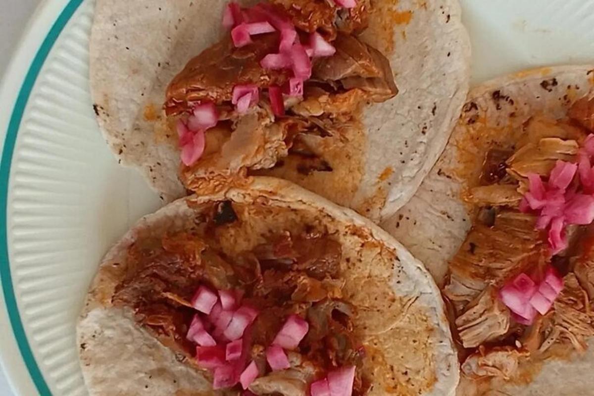 dua taco dengan daging dan bawang merah jambu di atas pinggan kertas