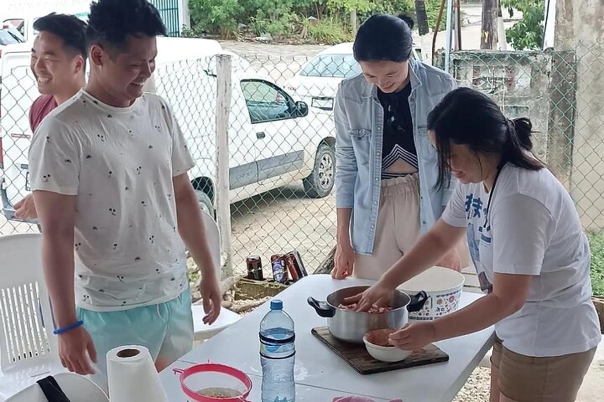 sekumpulan wanita berdiri mengelilingi meja menyediakan makanan
