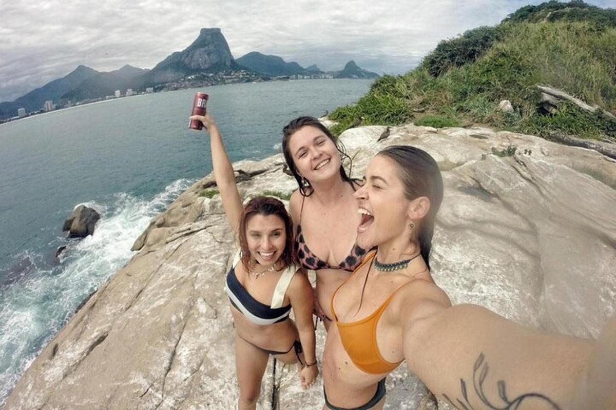 三个穿着泳衣的女人坐在水边的岩石上