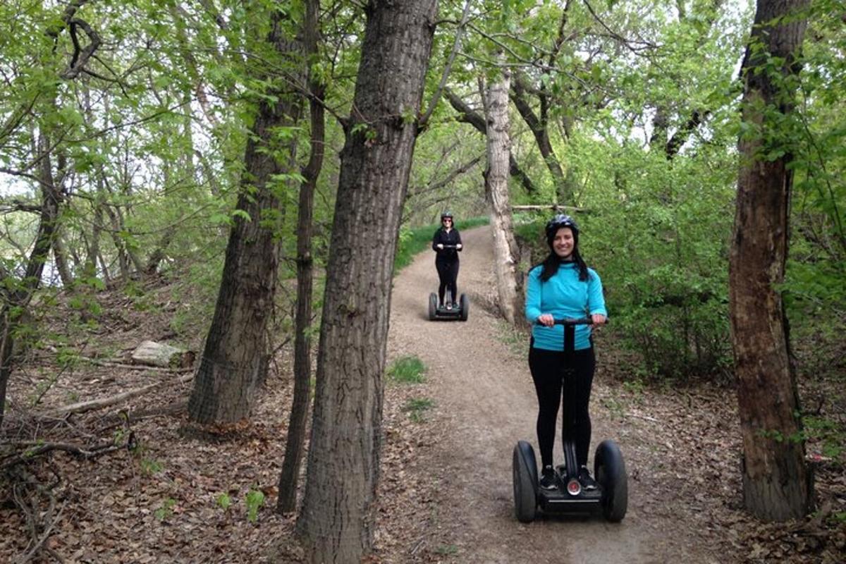 two people riding segways on a trail in the woods
