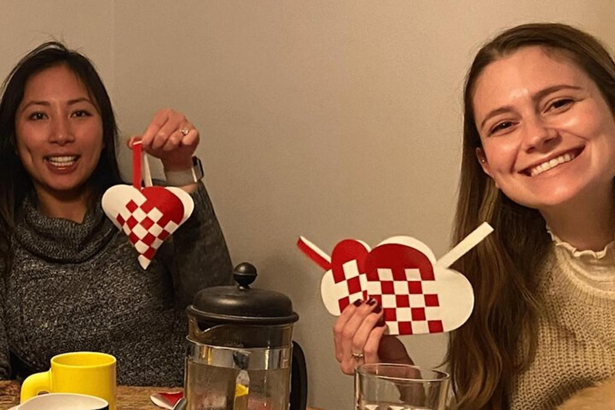 two women sitting at a table holding up paper hearts