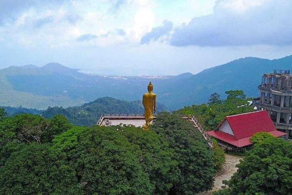 a statue on top of a hill with mountains in the background