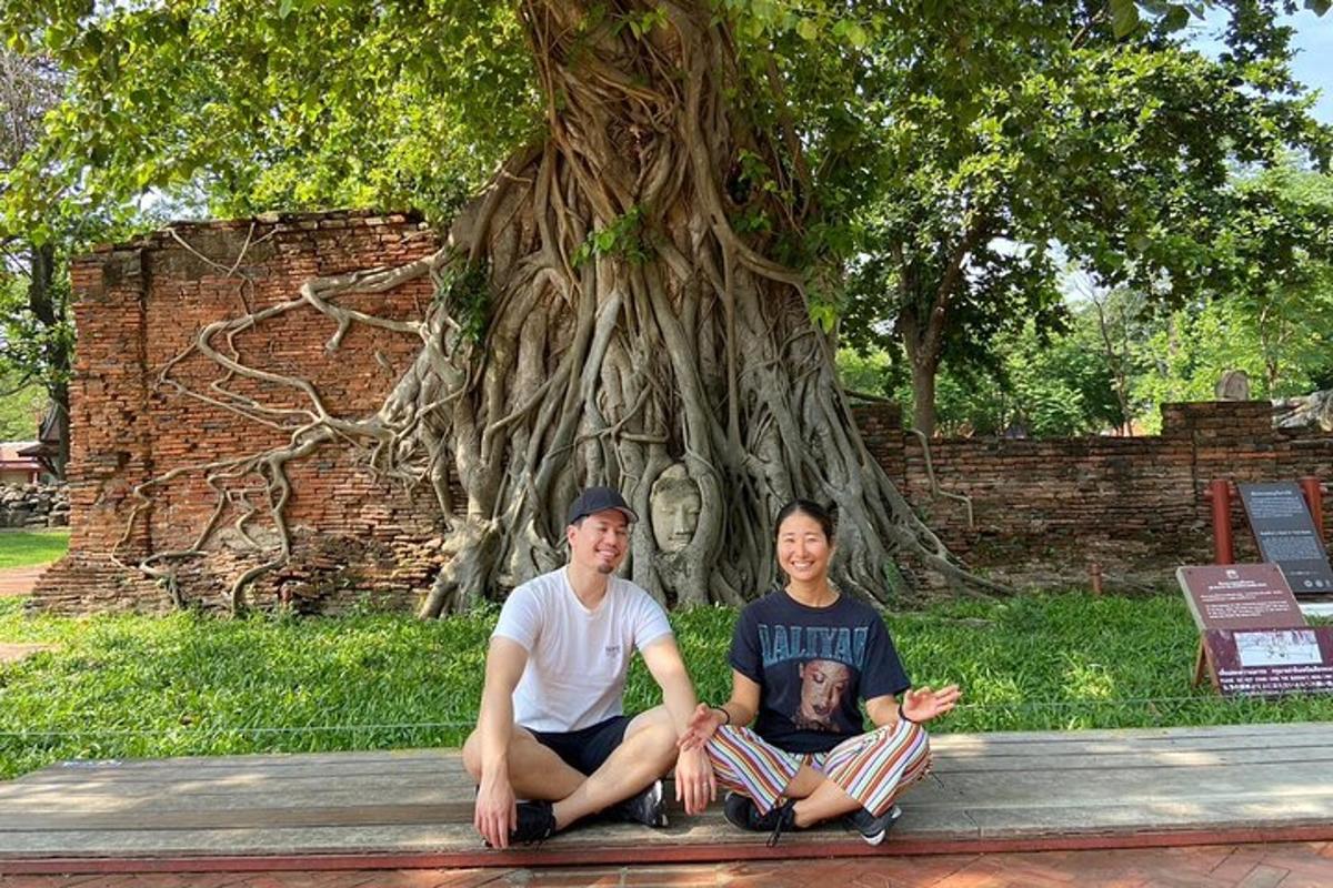dos personas sentadas en un banco frente a un árbol