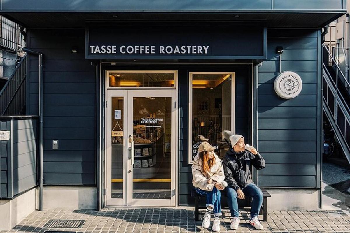 două persoane așezate pe o bancă în fața unei cafenele