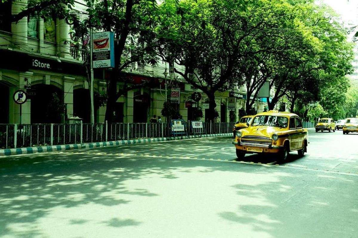 an old yellow car driving down a city street