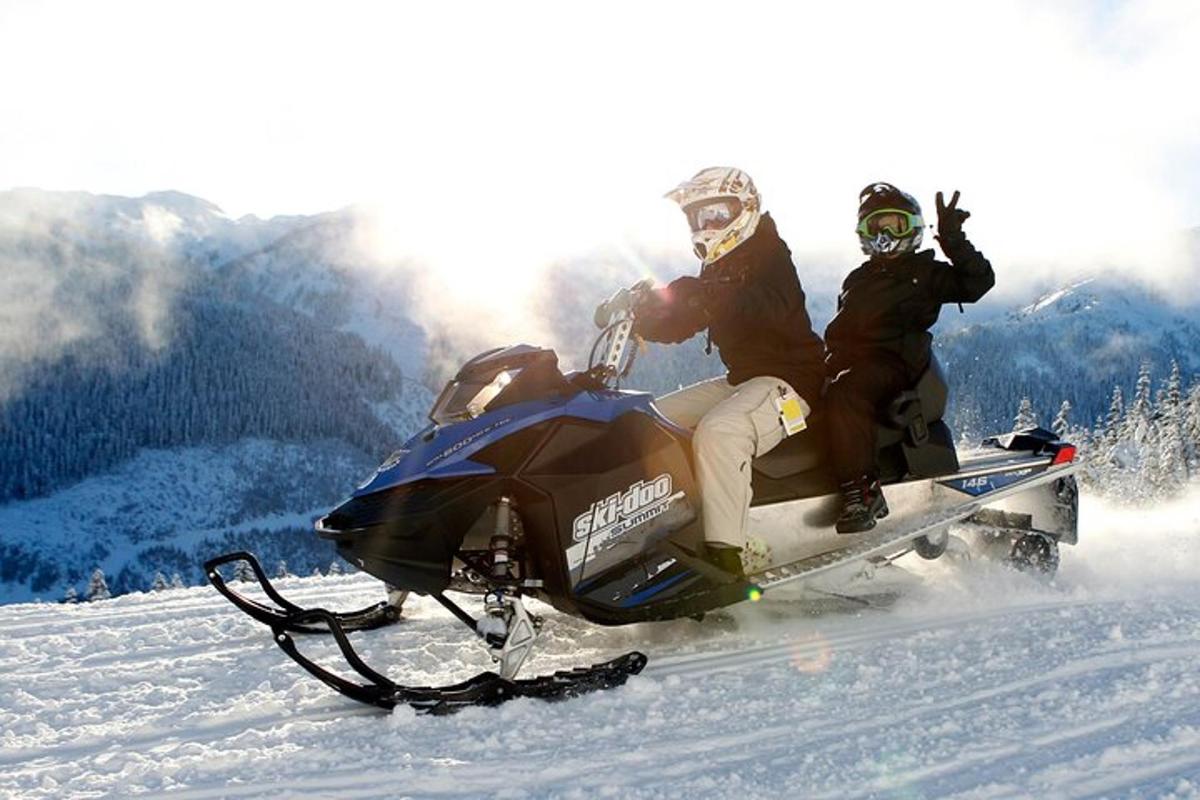 due persone in sella a una motoslitta sulla neve