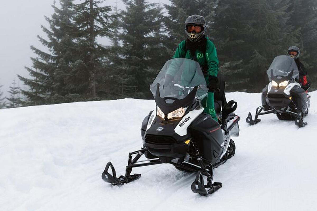 un uomo in piedi accanto a due persone sulla neve su una motoslitta