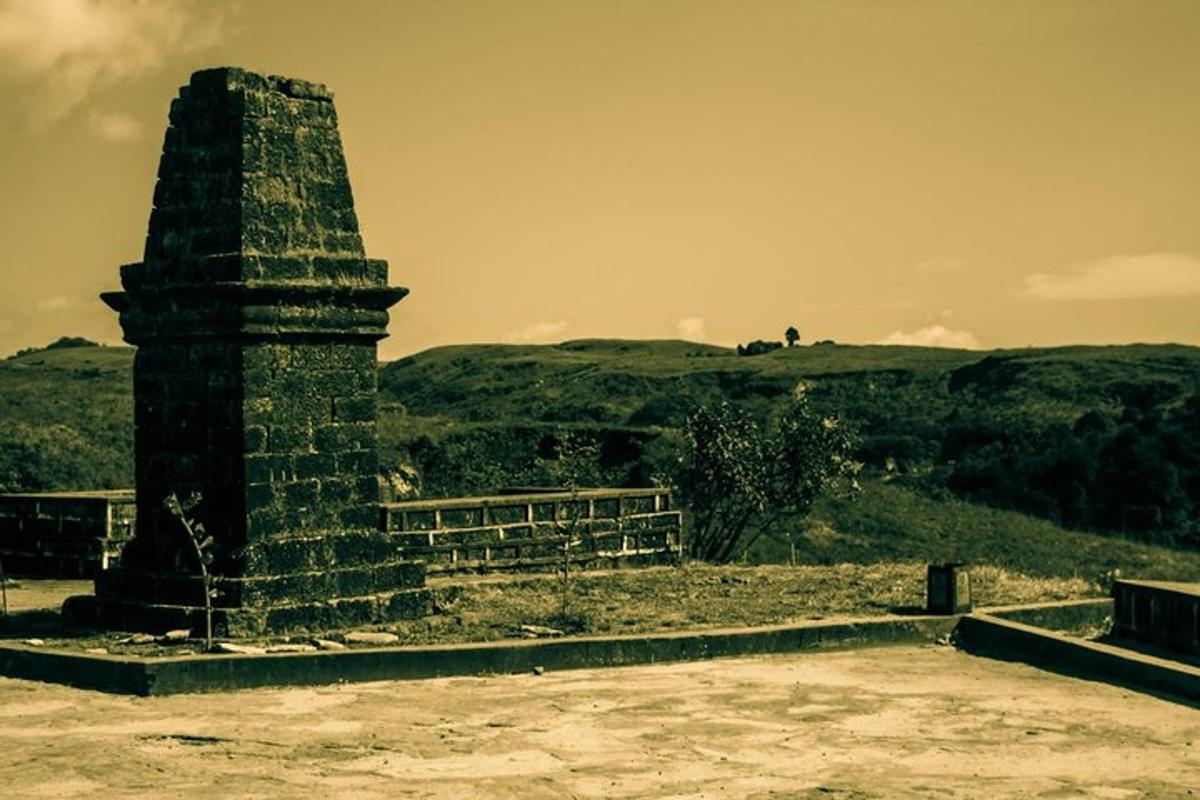 a stone monument on a field with hills in the background
