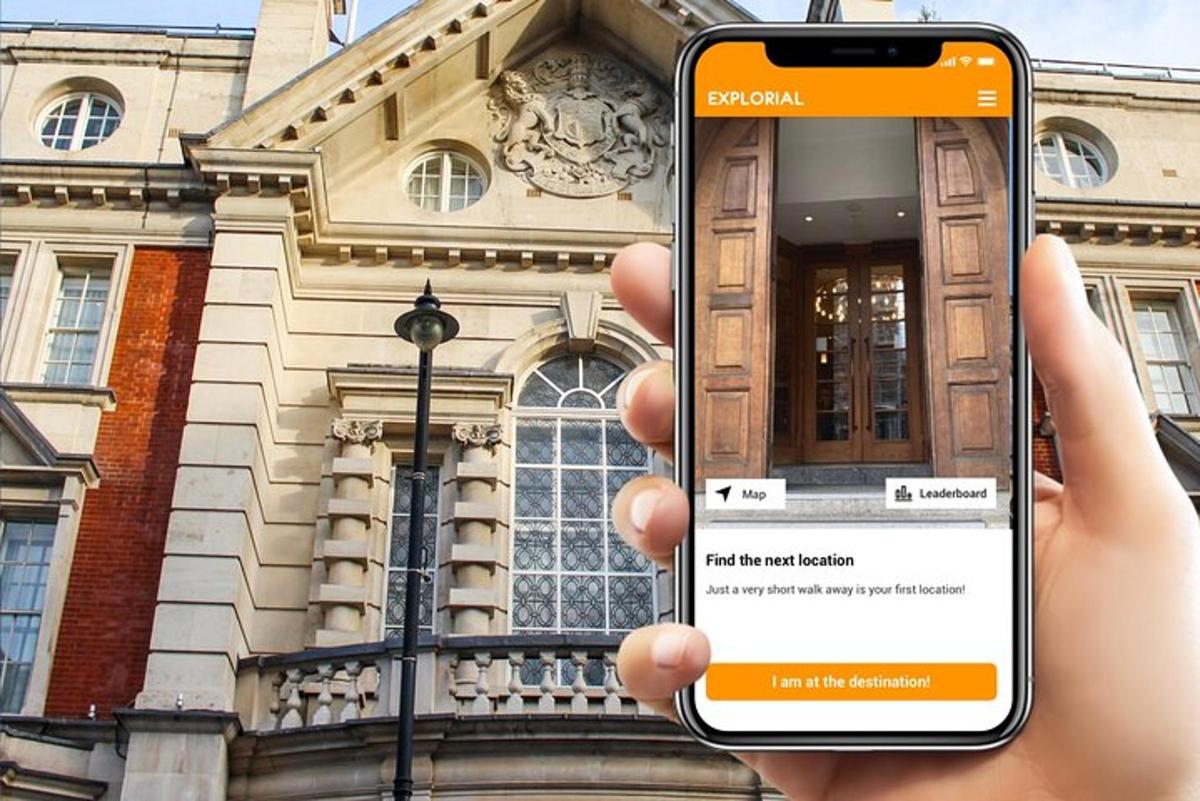 eine Person, die vor einem Gebäude ein Mobiltelefon hochhält