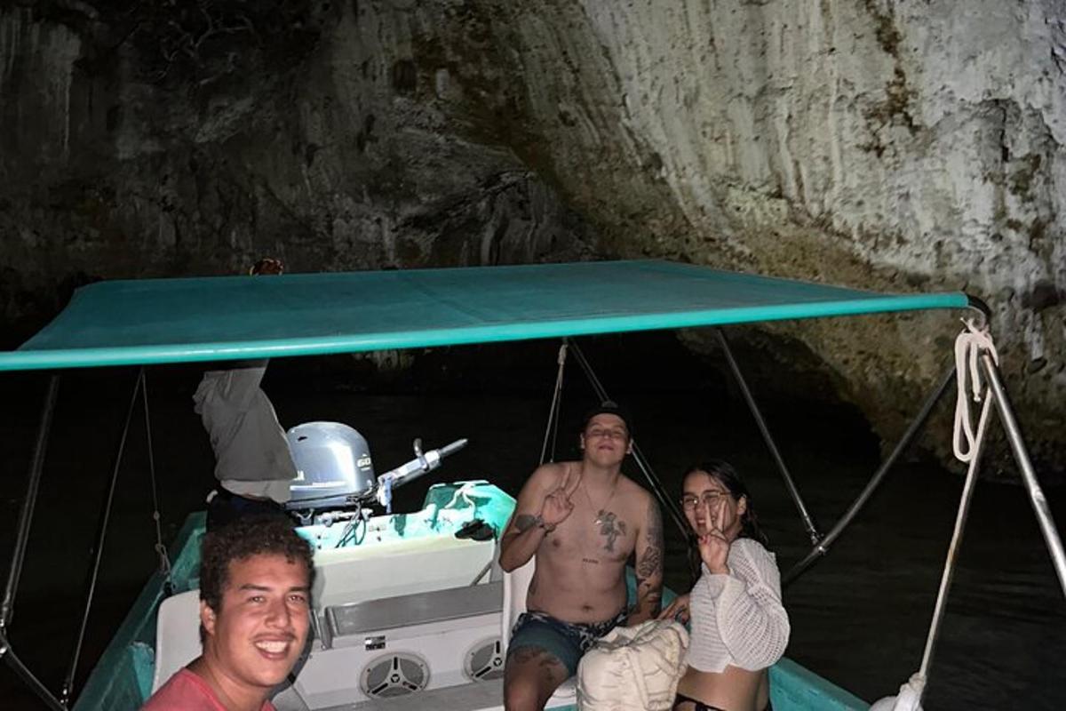 three men sitting on a boat in a cave
