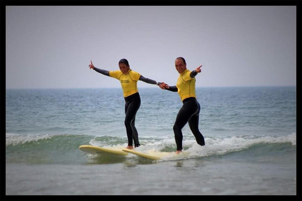 two men in yellow shirts riding a wave on a surfboard