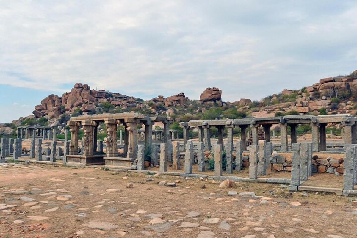 an ancient building with pillars in front of a mountain