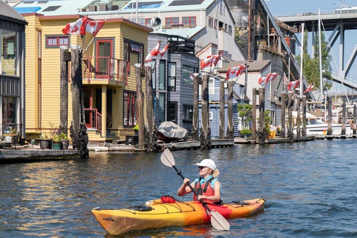 một người chèo thuyền kayak trên một dòng sông có nhiều tòa nhà