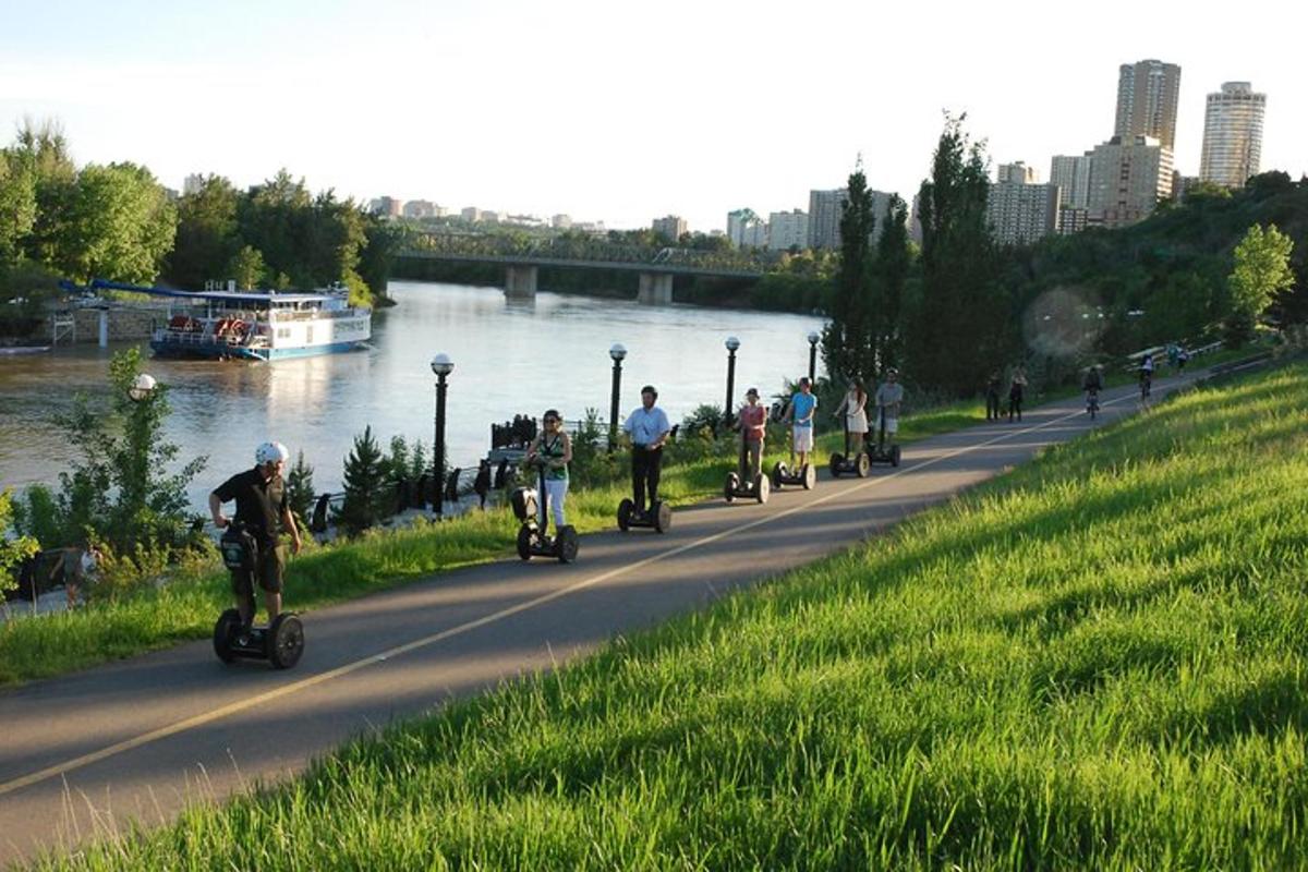 a group of people riding scooters on a path next to a river