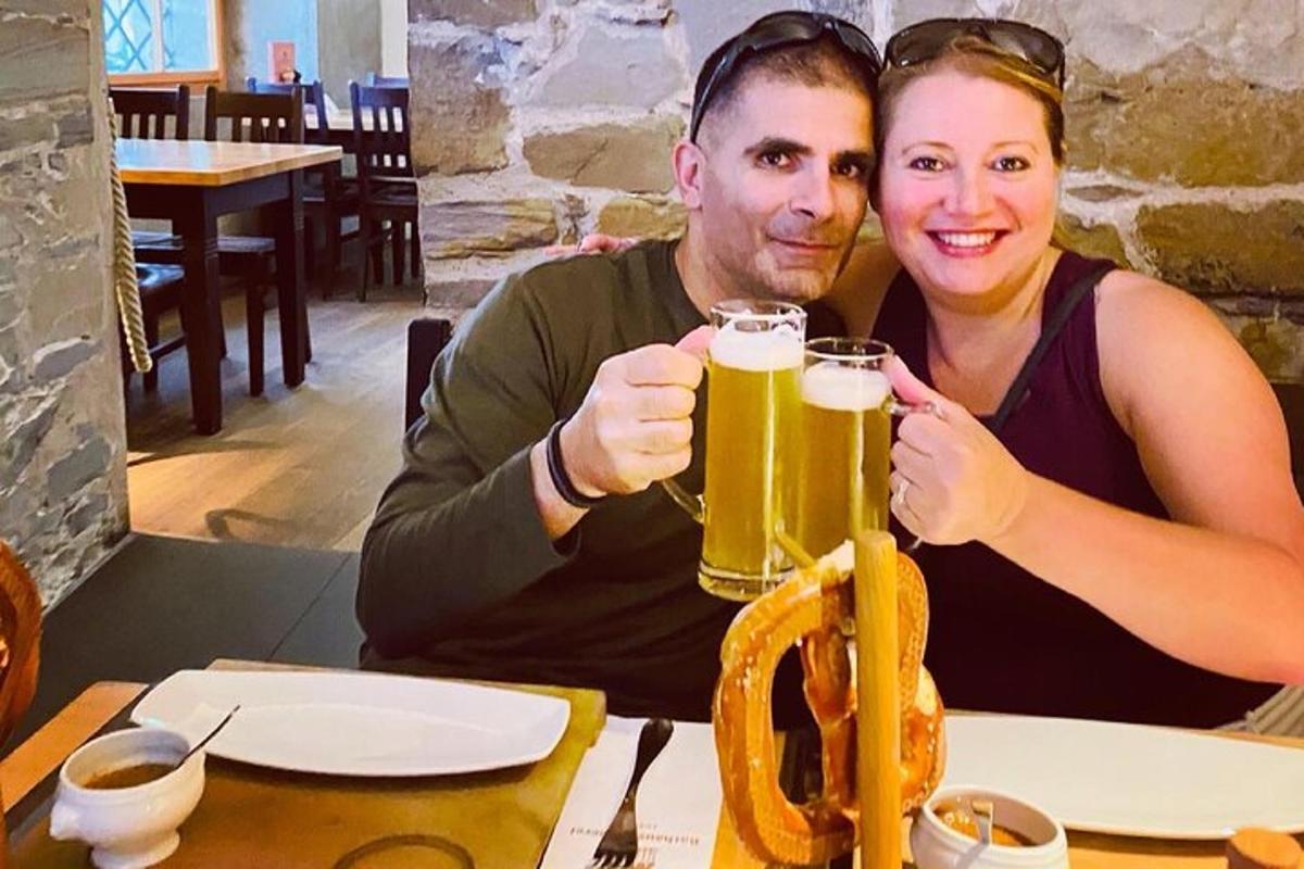 um homem e uma mulher sentados à mesa com uma cerveja