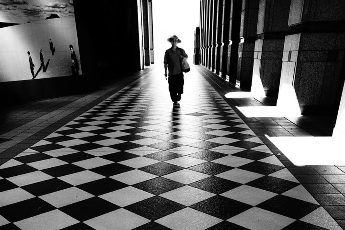 Un hombre caminando por un pasillo con suelo a cuadros.