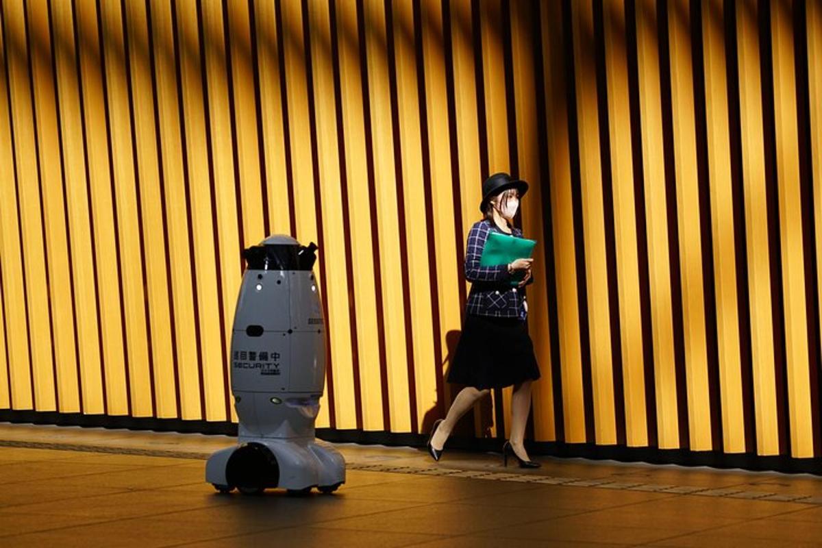 Una mujer está de pie junto a un robot.