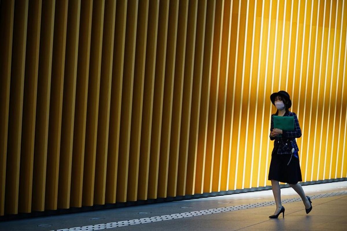 a woman walking in front of a yellow wall