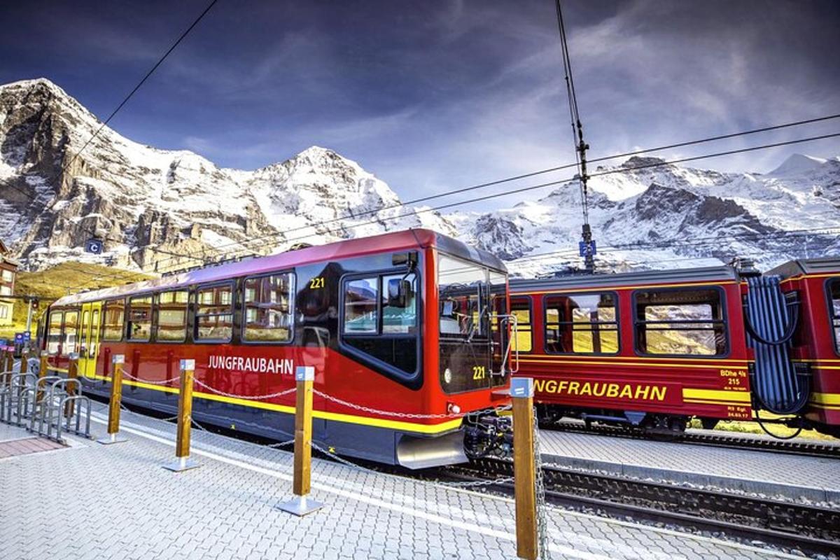 a red train on the tracks in front of a mountain