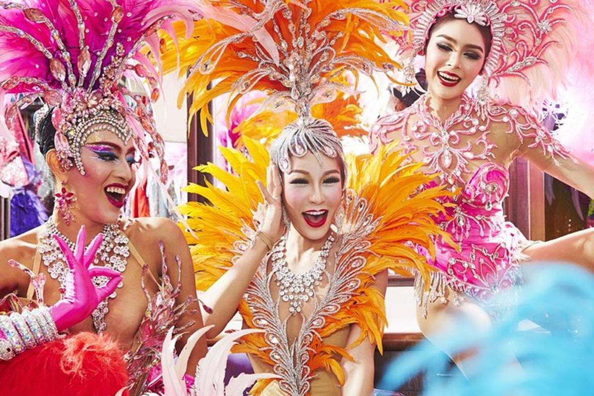 tiga wanita dalam pakaian berwarna-warni memakai topeng dan bulu