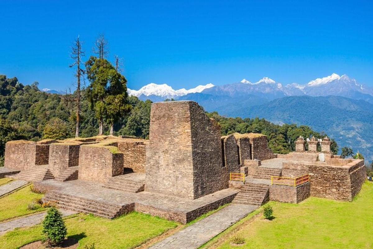 an old building on a hill with mountains in the background