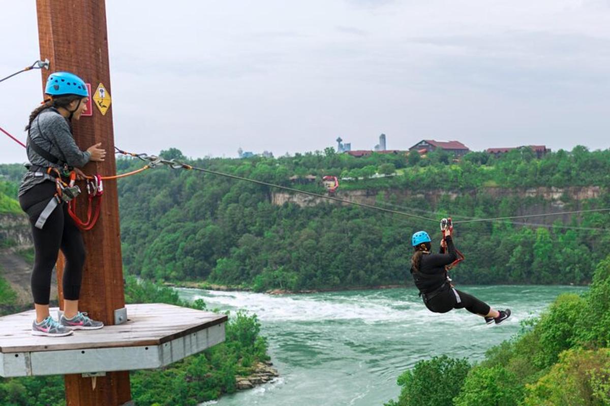 two people are on a zip line over a river