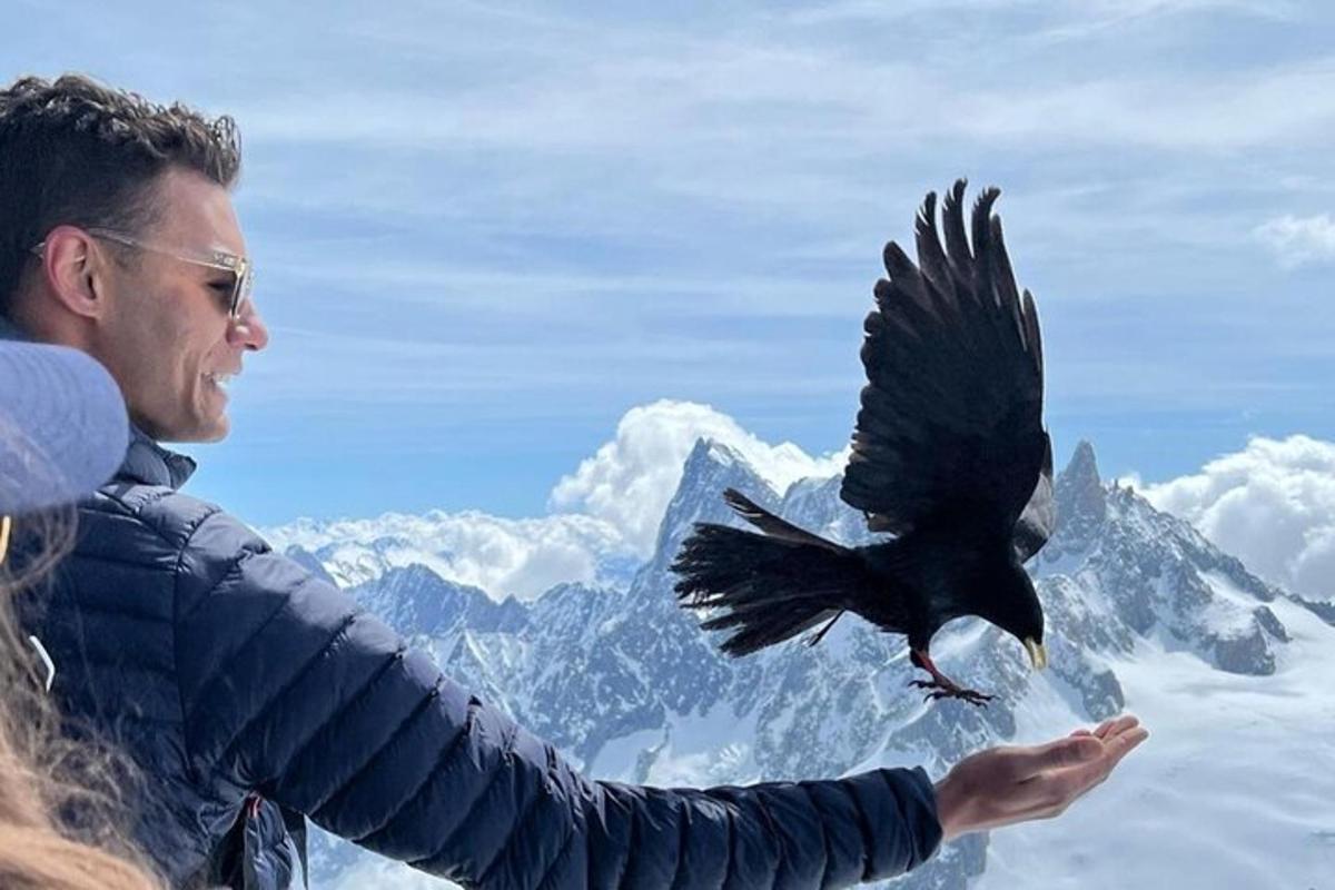 seorang lelaki memegang burung terbang di atas gunung