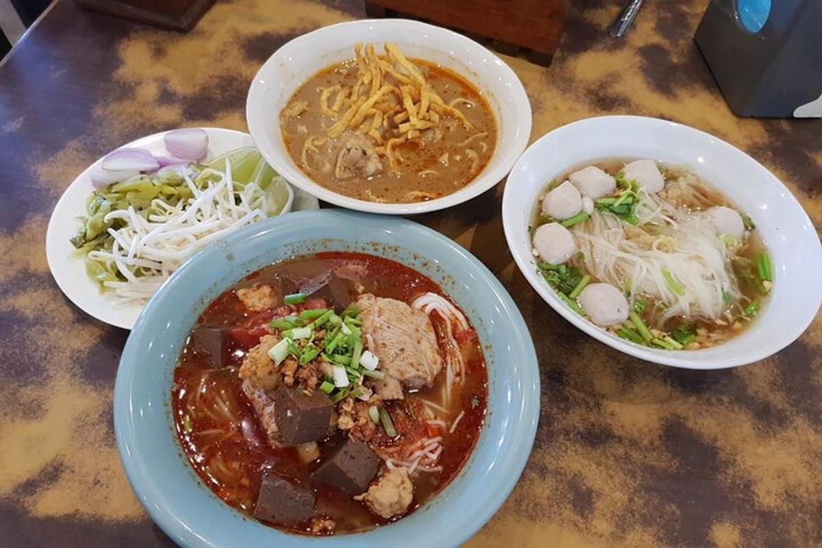 sebuah meja di atasnya dengan tiga mangkuk sup dan mee