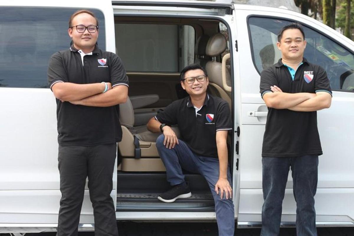 three men standing in front of a van