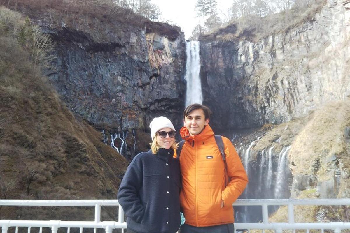 a man and woman standing in front of a waterfall