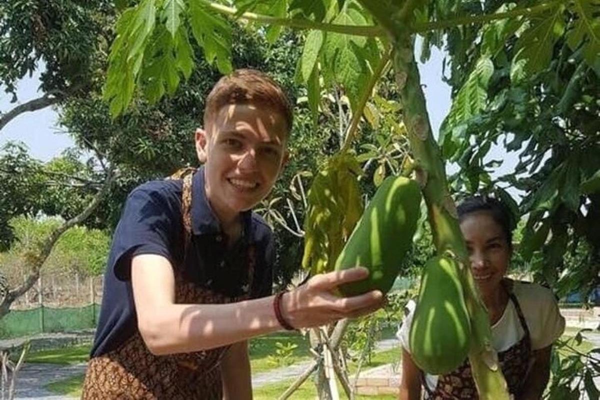 a man is holding a bunch of green bananas