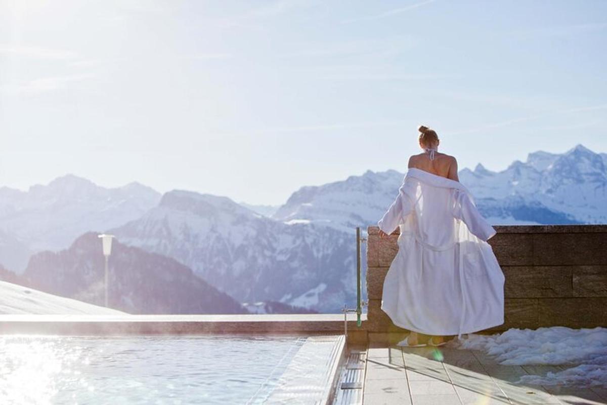 a woman in a white dress standing on a wall overlooking mountains