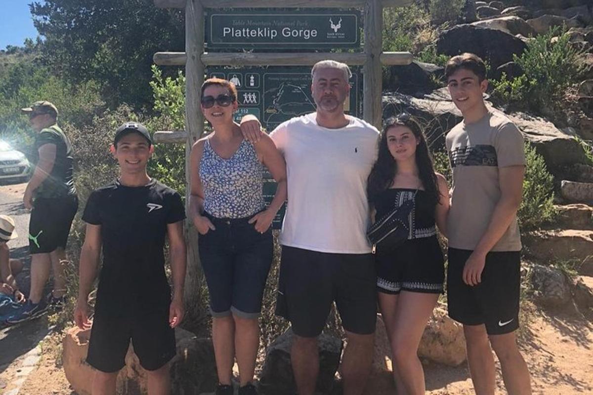 un uomo e la sua famiglia in piedi davanti a un cartello